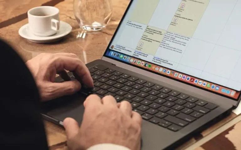 Notebook aberto com planilha na tela ao lado de uma xícara de café