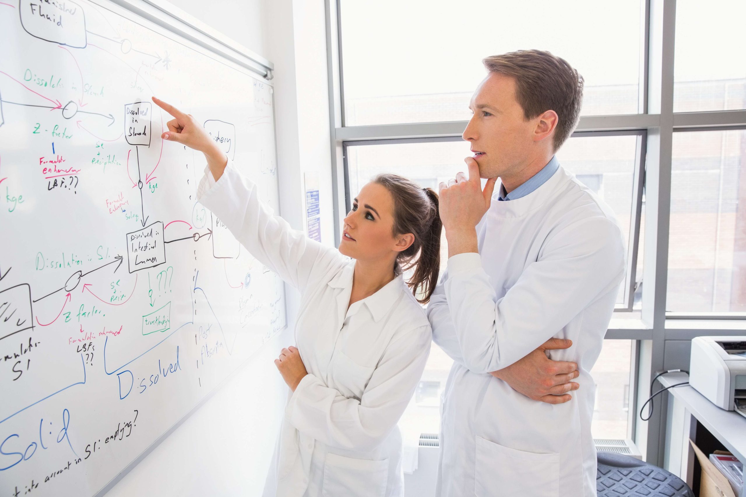 Science student and lecturer looking at whiteboard at the laboratory